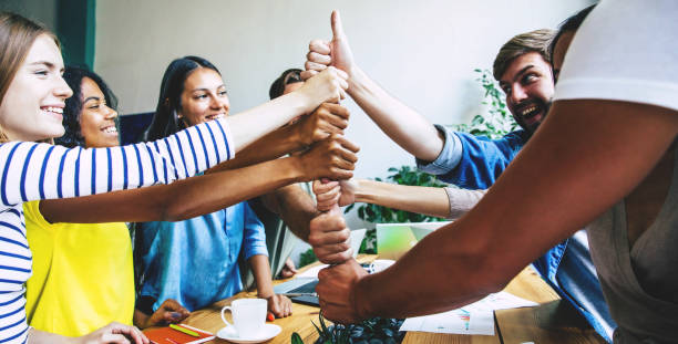 group of happy, excited and successful modern people in office. start up business team are holding hands together in circle. company of young students are celebrating some win. - hands clasped business education cooperation imagens e fotografias de stock