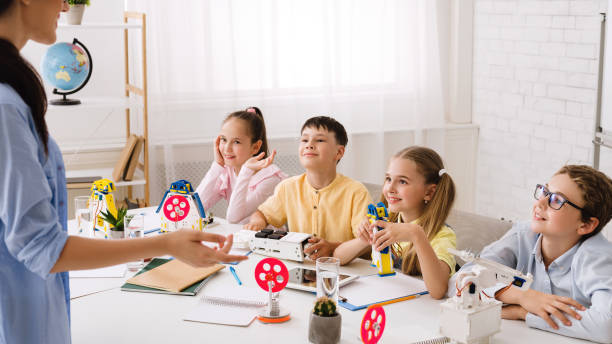 istock Teacher explaining new material to children, kids creating robots 1173539922
