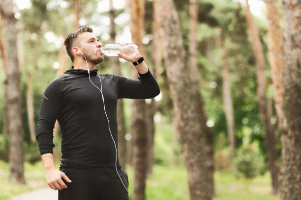 istock Young athletic man drinking water after training in city park 1173540477