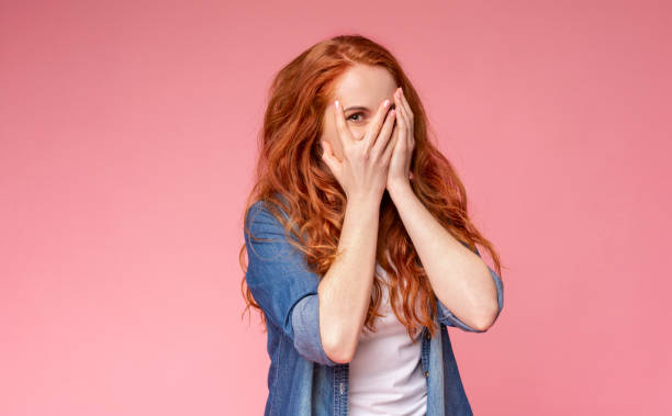 istock Curious girl peeking through fingers, covering face with both hands 1173541065