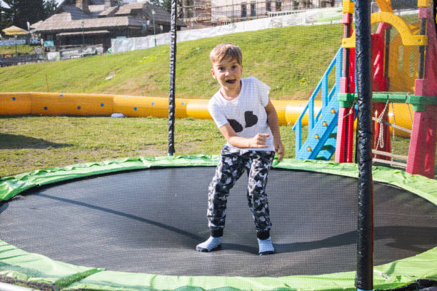 Happy kid having fun while jumping on trampoline and looking at camera.
