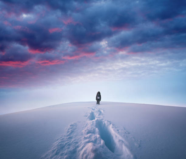 Winter Hike Woman hiking to the top of a snowcapped mountain peak at sunset. snow sunset winter mountain stock pictures, royalty-free photos & images