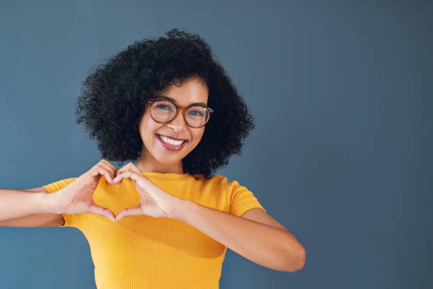 Much love Studio portrait of an attractive young woman showing the heart sign while standing against a grey background peace demonstration photos stock pictures, royalty-free photos & images