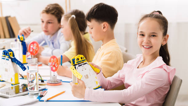 istock Happy schoolgirl holding robot model in classroom 1173546376