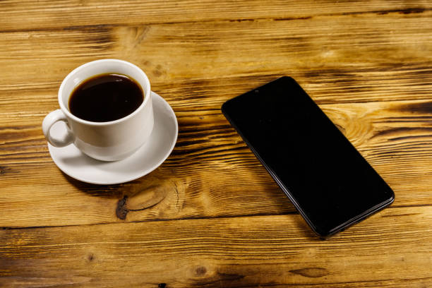istock Cup of coffee and smartphone on a wooden table 1173548047