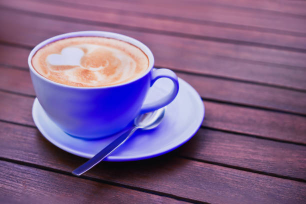 Cup of coffee in neon light on wooden table. Copy space.