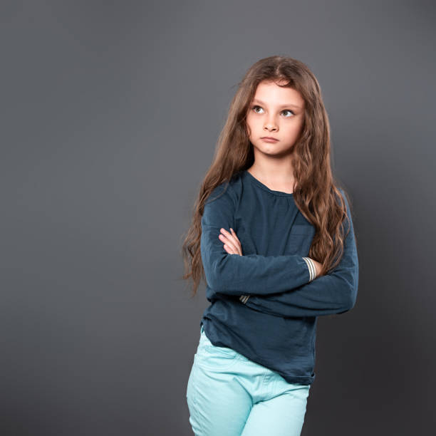 istock Thinking casual pupil kid girl with folded arms thinking and looking up on grey studio 1173550598