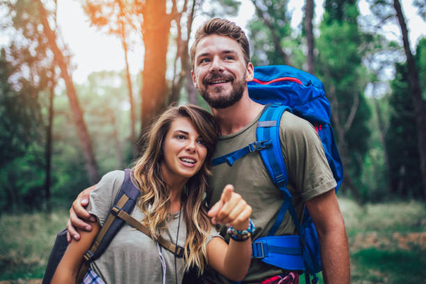 istock Smiling couple walking with backpacks over natural background 1173550650