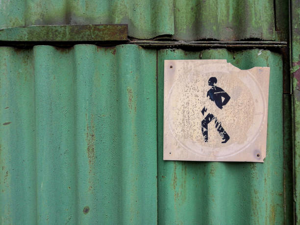старый выцветший символ запрета пешеходного прохода, расположенный на старом ржавом зеленом волнистом листе железа. гранж стиль. - sign rust old fashioned corrugated iron стоковые фото и изображения