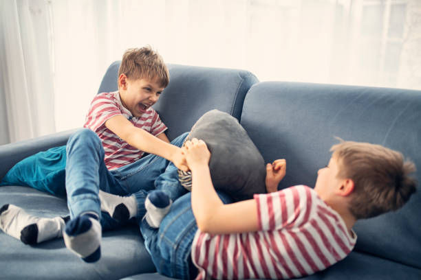 niños gemelos peleando en casa - lucha con almohada fotografías e imágenes de stock