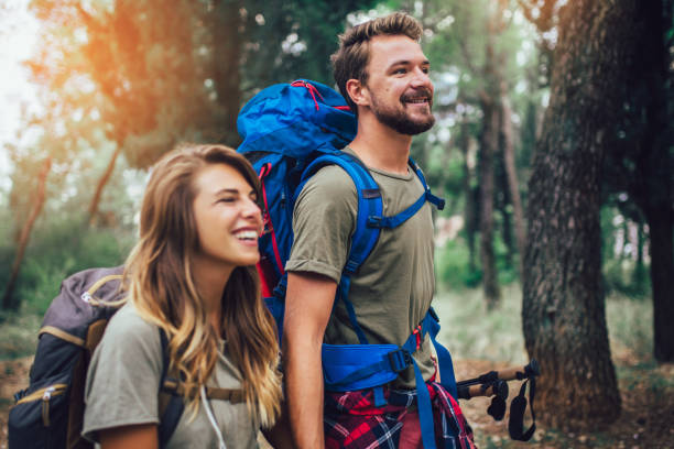 istock Smiling couple walking with backpacks over natural background 1173550786