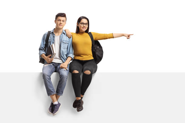 istock Male and female student sitting on a panel and pointing to the side 1173554533