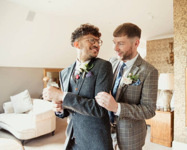 We're Better Together Married LGBTQ+ couple standing and looking at each other on their wedding day. They are dressed in suits and smiling. lgbtqia culture photos stock pictures, royalty-free photos & images