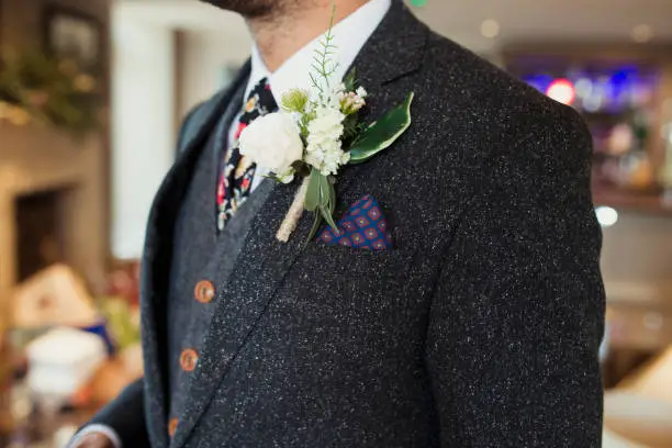 Close up of a boutonniere fastened onto a suit jacket.