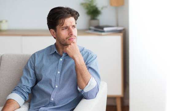 istock Guy Thinking Looking Aside Sitting On Couch At Home 1173557800
