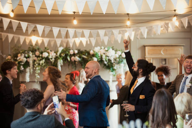 Weddings Are The Best Parties Wedding guests of mixed ages dressed smartly dancing at a wedding reception dancing with one another. One man is doing a fist pump and another is taking a video. whimsical wedding stock pictures, royalty-free photos & images