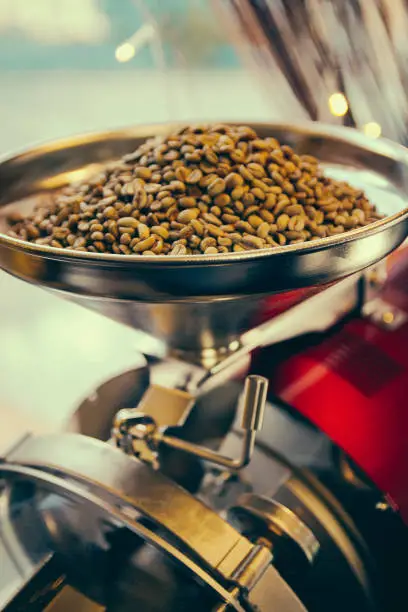 Photo of Roaster machine prepared coffee beans.  Process of coffee roasting in cafe. Ingridient for popular european drink. Brown bean inside box. Organic food. Close up shot.