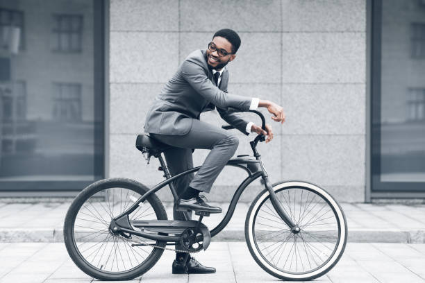 Keep calm and ride on. Businessman cycling against office buiding Keep calm and ride on. Businessman cycling against office buiding, going to work super bike stock pictures, royalty-free photos & images