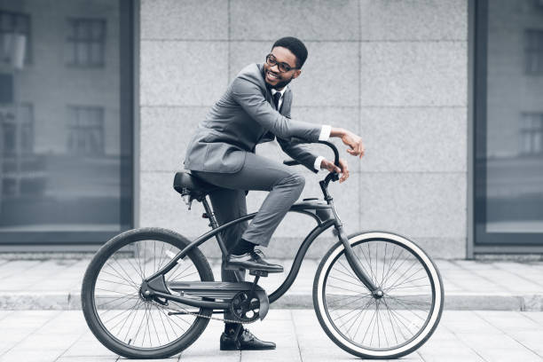 mantenha a calma e ande. homem de negócios que ciclagem de encontro ao buiding do escritório - african descent cycling men bicycle - fotografias e filmes do acervo