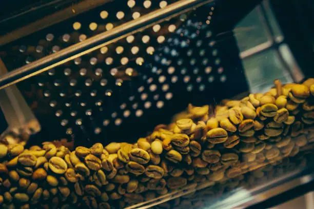 Photo of Roaster machine prepared coffee beans.  Process of coffee roasting in cafe. Ingridient for popular european drink. Brown bean inside box. Organic food. Close up shot.