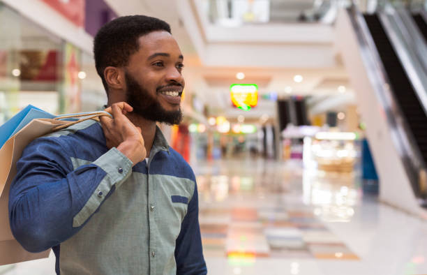Handsome african guy with paper bags happy after shopping Handsome african guy with paper bags happy after shopping in city mall, free space rich black men pictures stock pictures, royalty-free photos & images
