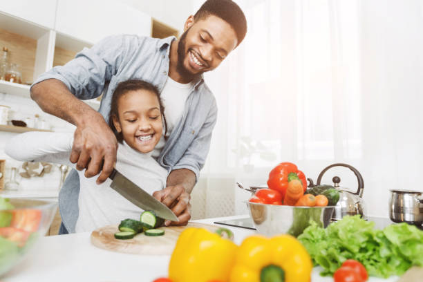 istock Dad teaching little girl how to use knife 1173560802