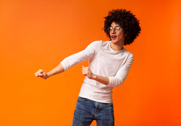 istock Cheerful bushy black man dancing on orange background 1173560973