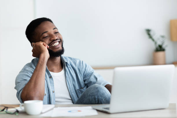 istock African guy talking on phone, working on laptop in office 1173563907