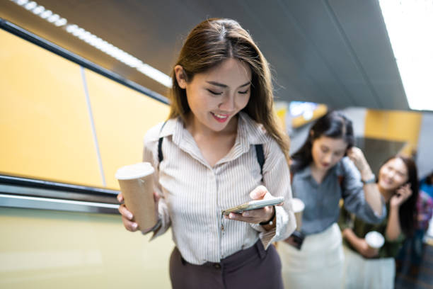 istock Asian woman on escalator using smart phone 1173564094