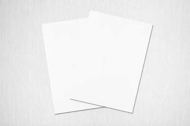 Photo of Two empty white rectangle poster or card mockups lying diagonally on top of each other