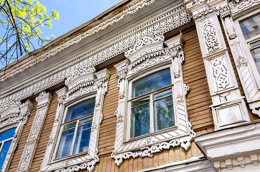 Russian traditional wooden architecture. Facade of an old house decorated with wooden carvings, platbands, wooden lace ornament