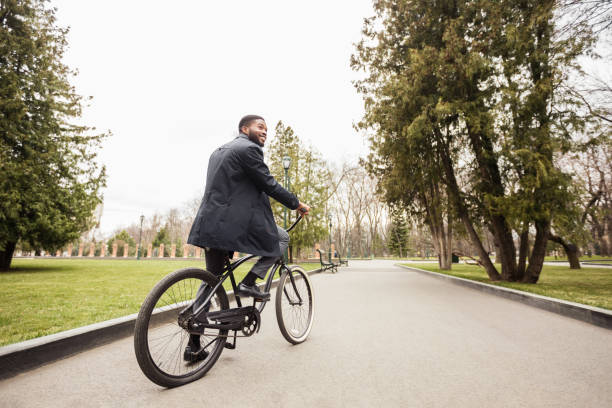 istock Millennial afro businessman riding bicycle to work in park 1173567197