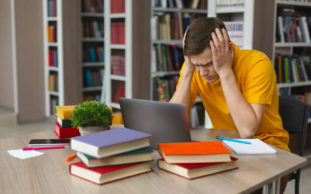istock Tired student sitting in front of laptop, clenching head 1173567278
