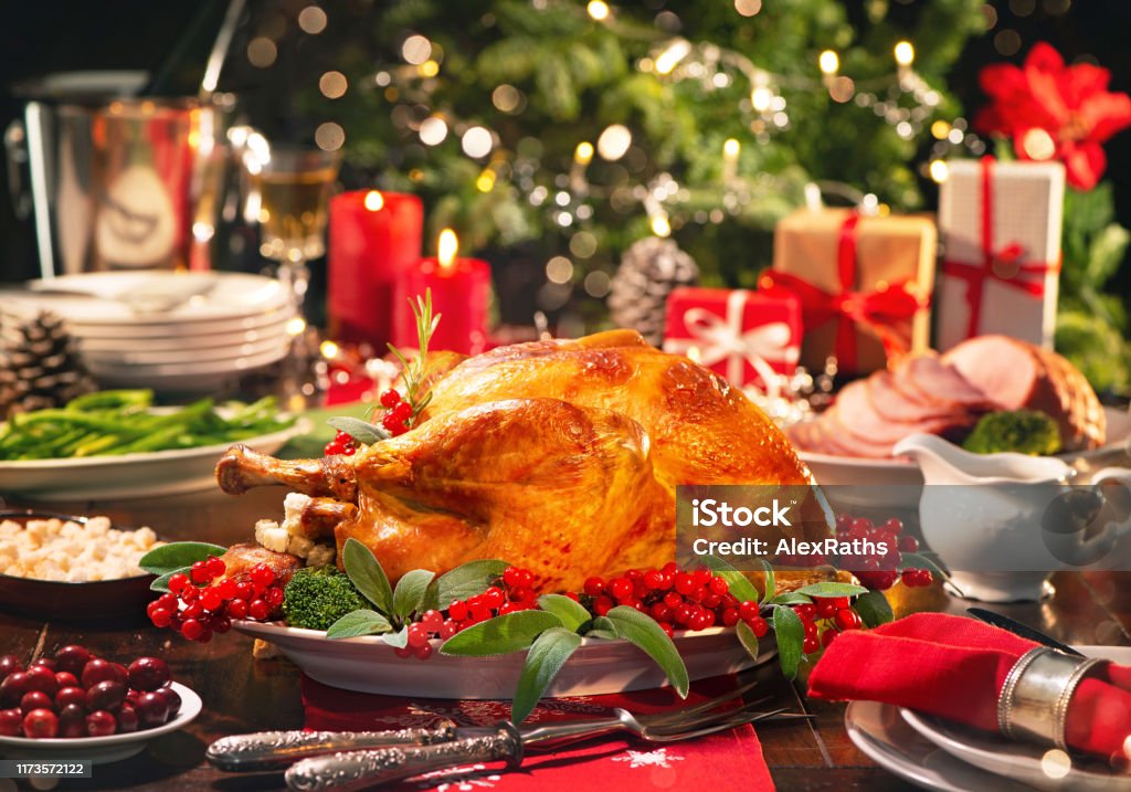 Christmas turkey dinner Christmas turkey dinner. Baked turkey garnished with red berries and sage leaves in front of Christmas tree and burning candles Christmas Stock Photo