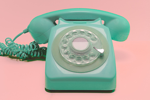 Old Fashioned Rotary Telephone in Turquoise With Coral Background