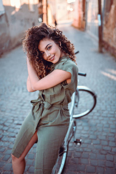Pretty girl posing on bicycle, rustic old town in background. Artistic image