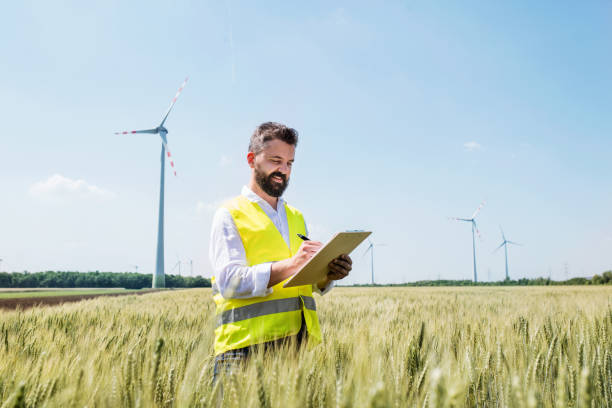 풍력 발전 단지의 들판에 서서 메모를 하는 엔지니어. - engineer wind turbine alternative energy energy 뉴스 사진 이미지