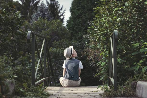 Kid sitting alone on a stairs in th garden stock photo