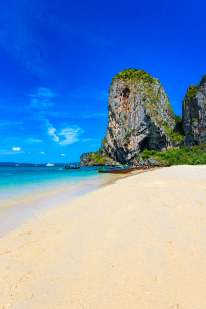 limestone karst rocks at ao phra nang beach with thai traditional wooden longtail boat on railay peninsula, close to ao nang, krabi province, andaman sea, thailand - phuket province beach blue cliff imagens e fotografias de stock