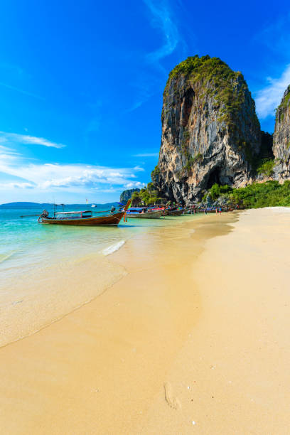 известняковые карстовые скалы на пляже ао пхра нанг с тайской традиционной деревянной длиннохвостой лодкой на полуострове райлай, недалек - phuket province beach blue cliff стоковые фото и изображения