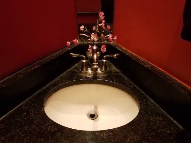 A red sink with gold faucet and running water