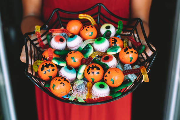 Woman offering funny Haloween candy at the front door Woman at the front door offering funny Halloween candies on a spiderweb shaped bowl. Unrecognizable person chocolate fingers stock pictures, royalty-free photos & images