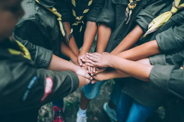 Group of young scouts joining hands together, showing their unity.