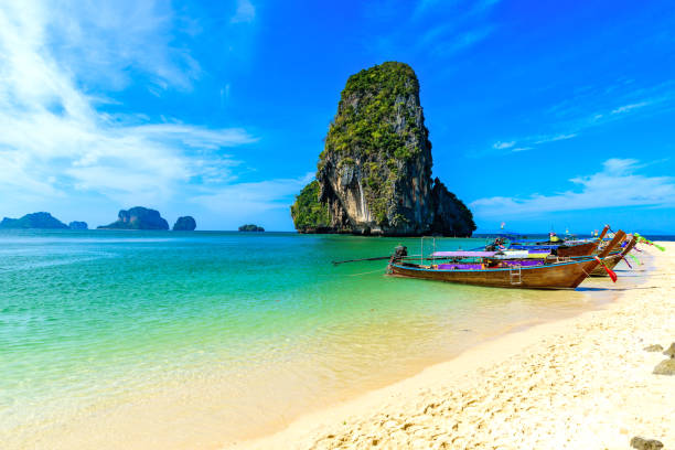 ao phra nang beach - тайская традиционная деревянная длиннохвостая лодка на полуострове райлай перед известняковыми карстовыми скалами, недалеко � - phuket province beach blue cliff стоковые фото и изображения