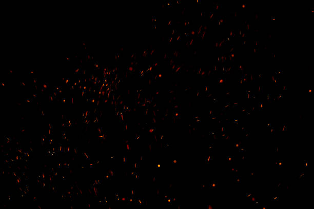 Burning red hot sparks fly from large fire in the night sky. Beautiful abstract background on the theme of fire, light and life.
