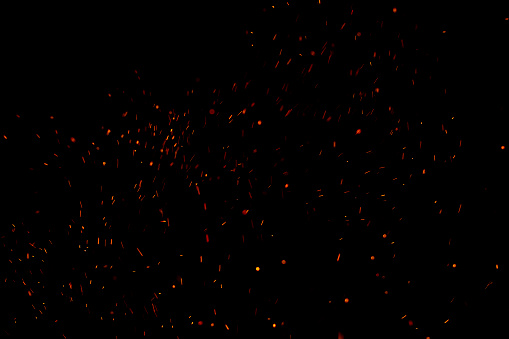 Burning red hot sparks fly from large fire in the night sky. Beautiful abstract background on the theme of fire, light and life.