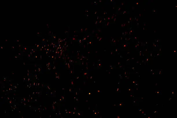 Burning red hot sparks fly from large fire in the night sky. Beautiful abstract background on the theme of fire, light and life.