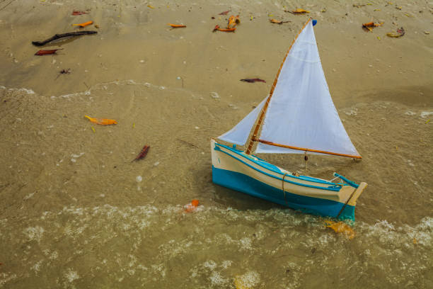 Macau/RN/Brasil: Boy playing on the beach with wooden boat built by his grandfather.