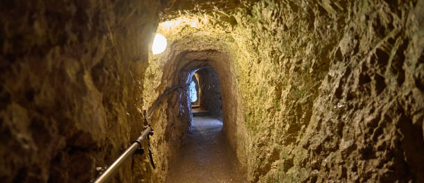 天井に電気ランプを備えた石灰岩で作られた山の狭いトンネルを通して見る。 - ravine geology danger footpath ストックフォトと画像