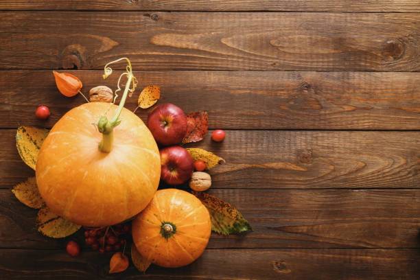 istock Creative Top view flat lay autumn composition. Pumpkins, dried fall leaves, apples, red berries, walnuts on wooden background. Thanksgiving, Halloween, Autumn Harvest concept 1173589406